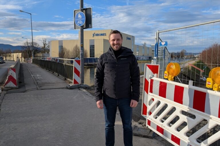 Daniel Artmann steht auf einem Gehweg neben einer Baustelle. im Hintergrund sieht man das Krones-Gebäude.